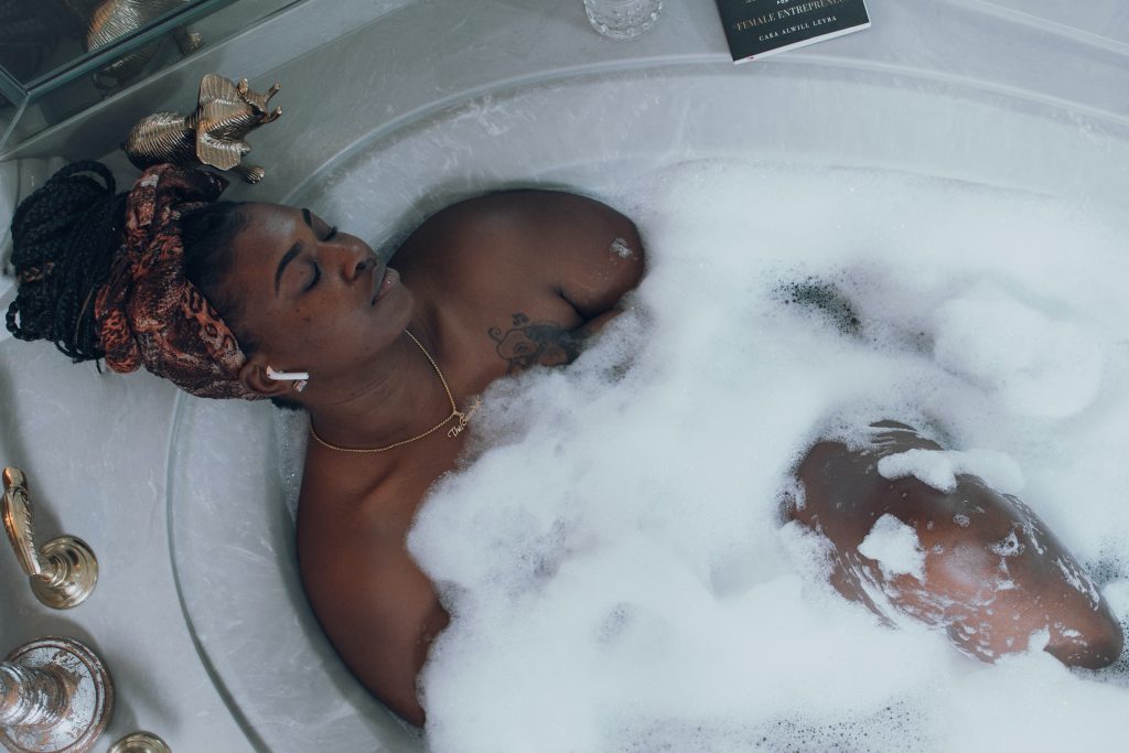 A Black woman relaxing in a bubble bath.